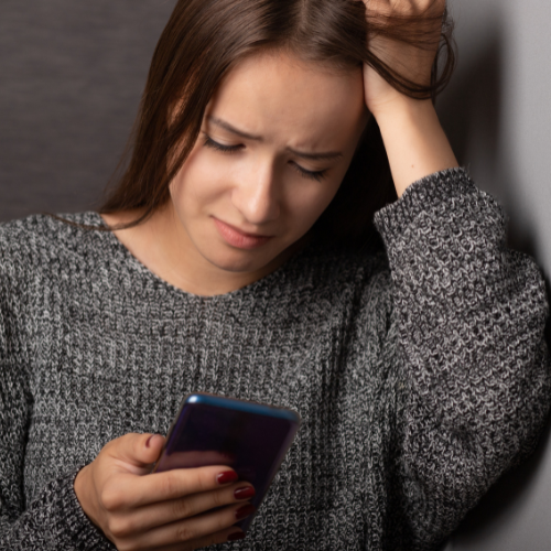 Harassed woman in Massachusetts looking at phone.