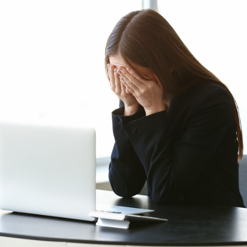 Woman crying at her computer due to harassment in Massachusetts.