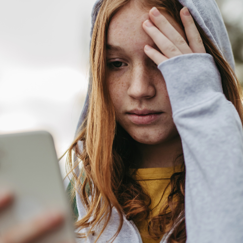 Woman looking at phone containing harassing texts in Massachusetts.