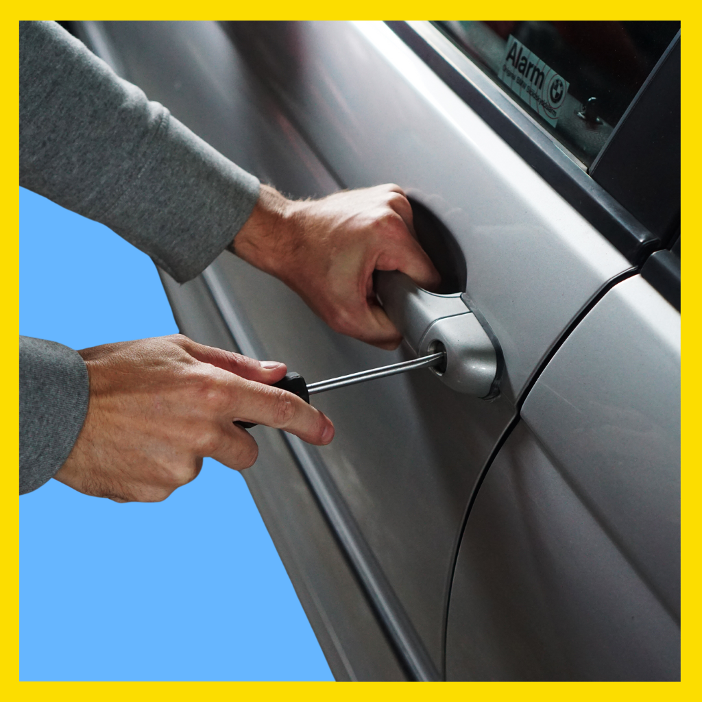 Man breaking into car using screwdriver.