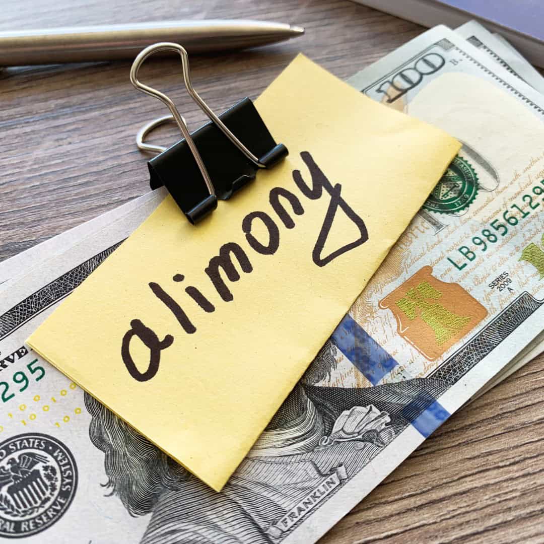 Massachusetts legal services - A sticky note with "alimony" written on it, placed on US dollar bills.