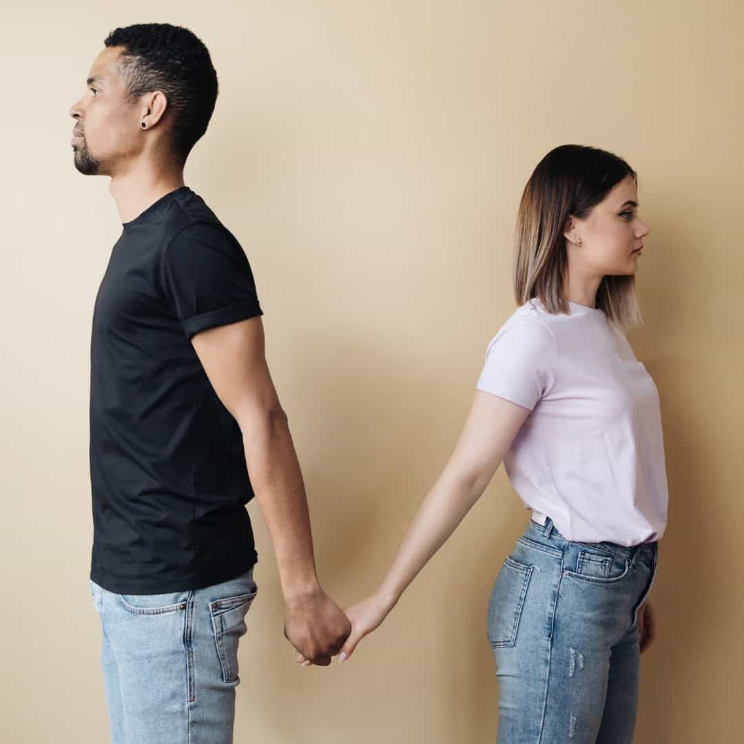 Massachusetts legal services - A man and woman holding hands, facing opposite directions, symbolizing relationship issues or separa.