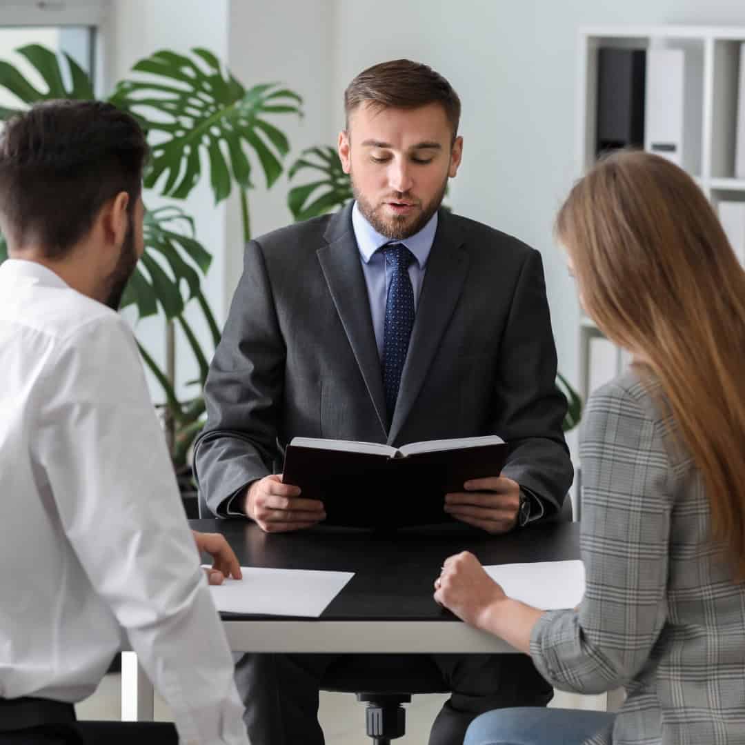 Massachusetts legal services - A man in a suit consulting with two clients in a legal office setting.