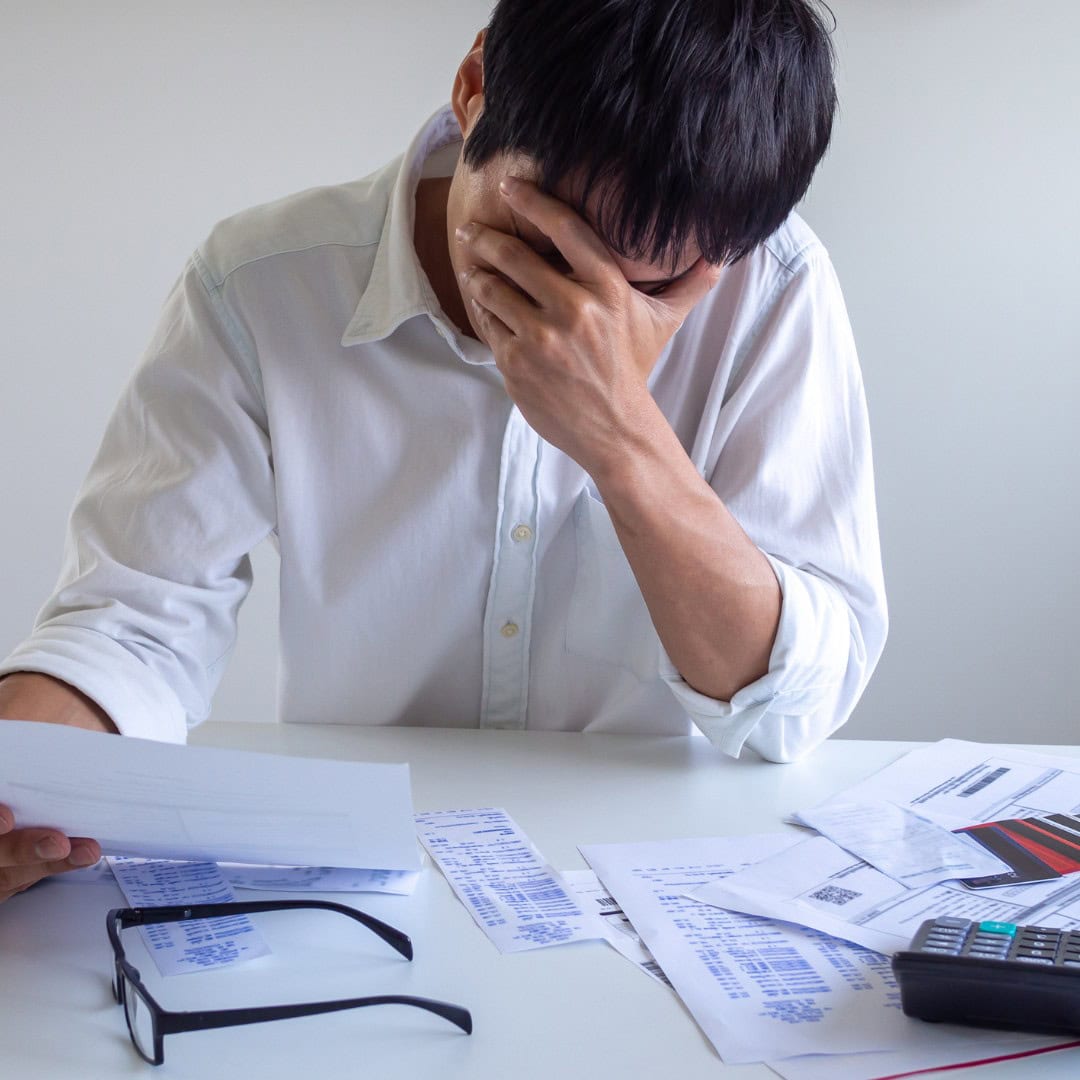 Resources 7 Massachusetts legal services - A man in distress reviewing financial documents at a desk, representing financial or legal stress.