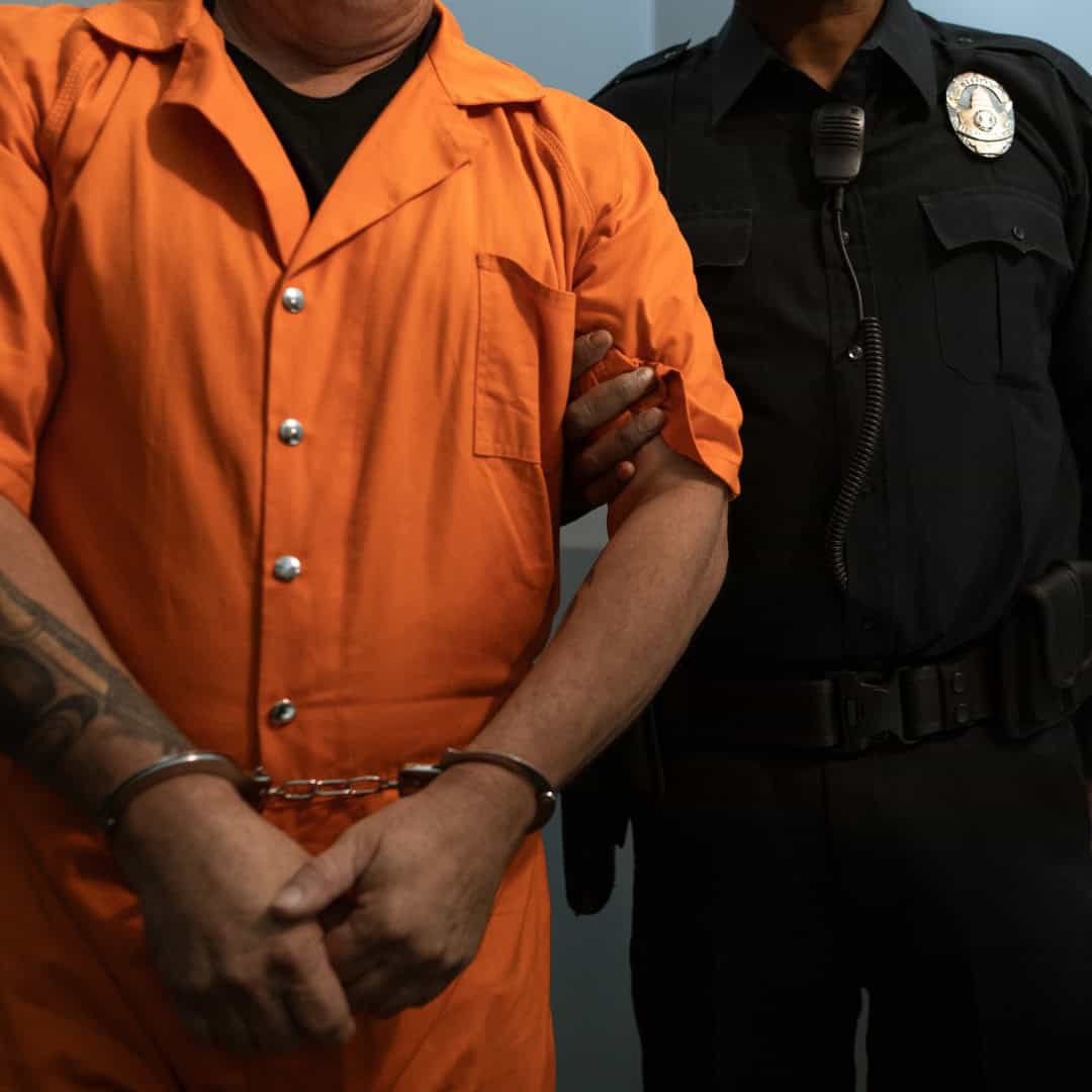 Resources 5 Man in orange jumpsuit being placed under arrest by police officer.