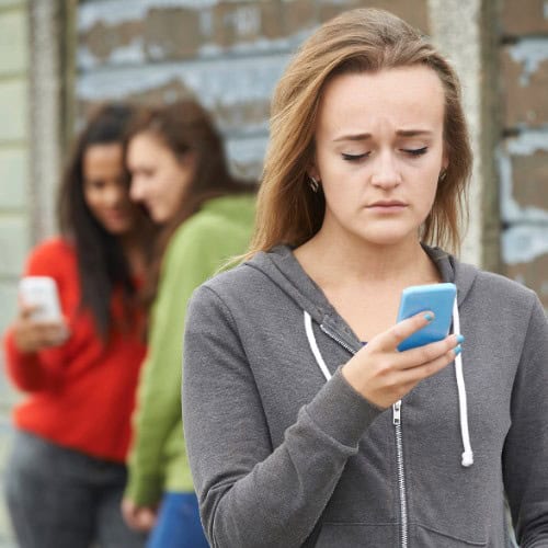 Woman looking at phone reading harassing text messages in Massachusetts.