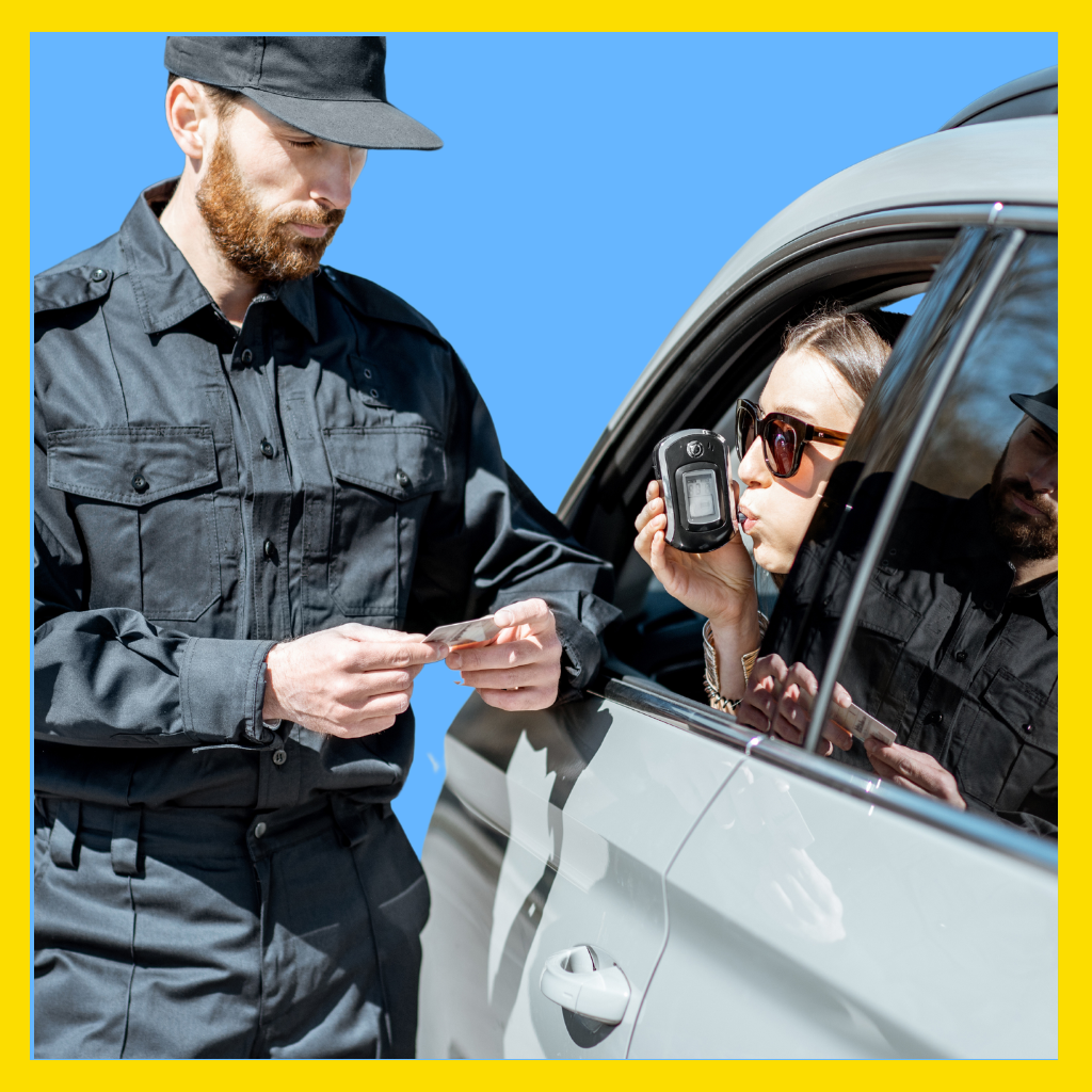 Woman driver blowing into portable breath test as a Massachusetts cop watches.