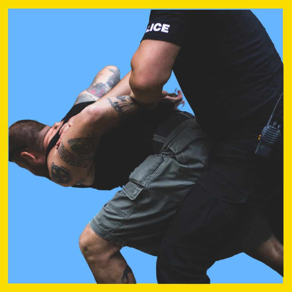 Massachusetts legal services - Man being restrained by police officer during an arrest, law enforcement action in Massachusetts.
